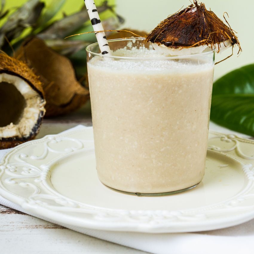 A delicious coconut margarita smoothie served on a plate, surrounded by fresh coconut leaves for decoration.