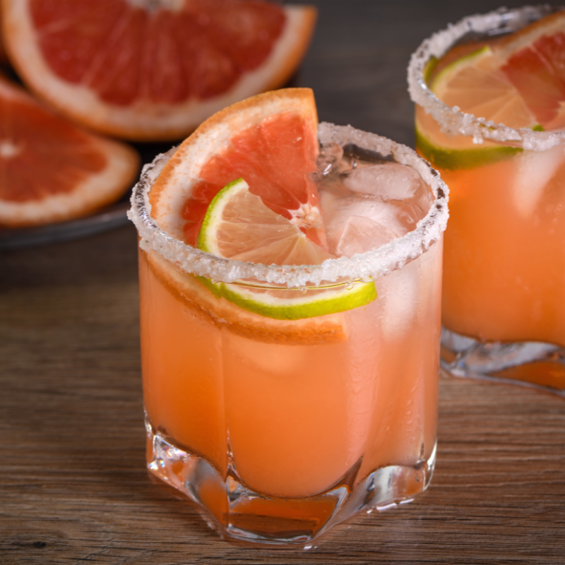 Two glasses of Pineapple Mint Paloma with slices of lime for a vibrant tropical drink perfect for the summer.