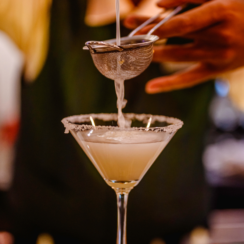 A person pours a Ginger Cosmopolitan into a glass.