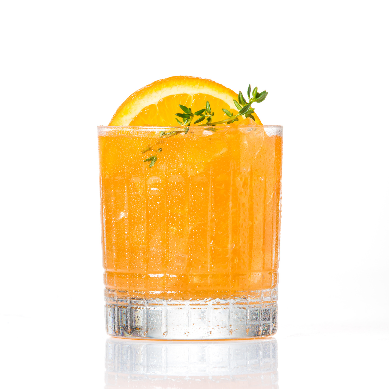 A colorful cocktail made with orange and thyme, served in a glass with a slice of orange and a sprig of thyme on top.