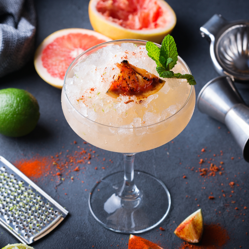 A vibrant Mezcal Paloma cocktail with lemon and grapefruit slices for a colorful and fun drink.
