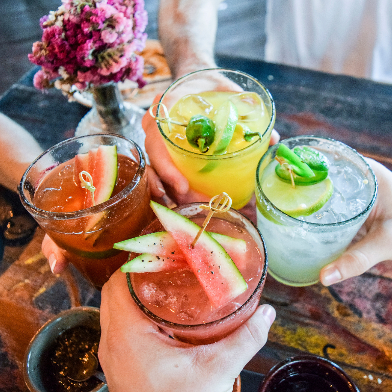 A group toasts with lively cocktails featuring watermelon, lime and cucumber.