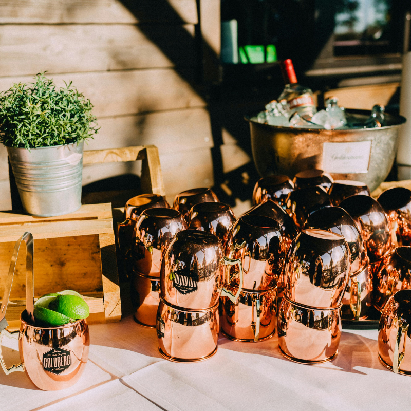 A table with copper mugs and bottles, perfect for enjoying a refreshing Moscow Mule drink.