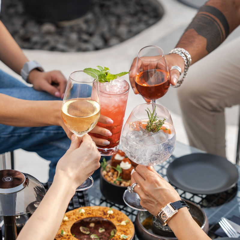 Friends clinking glasses, enjoying tasty drinks on a hot day.