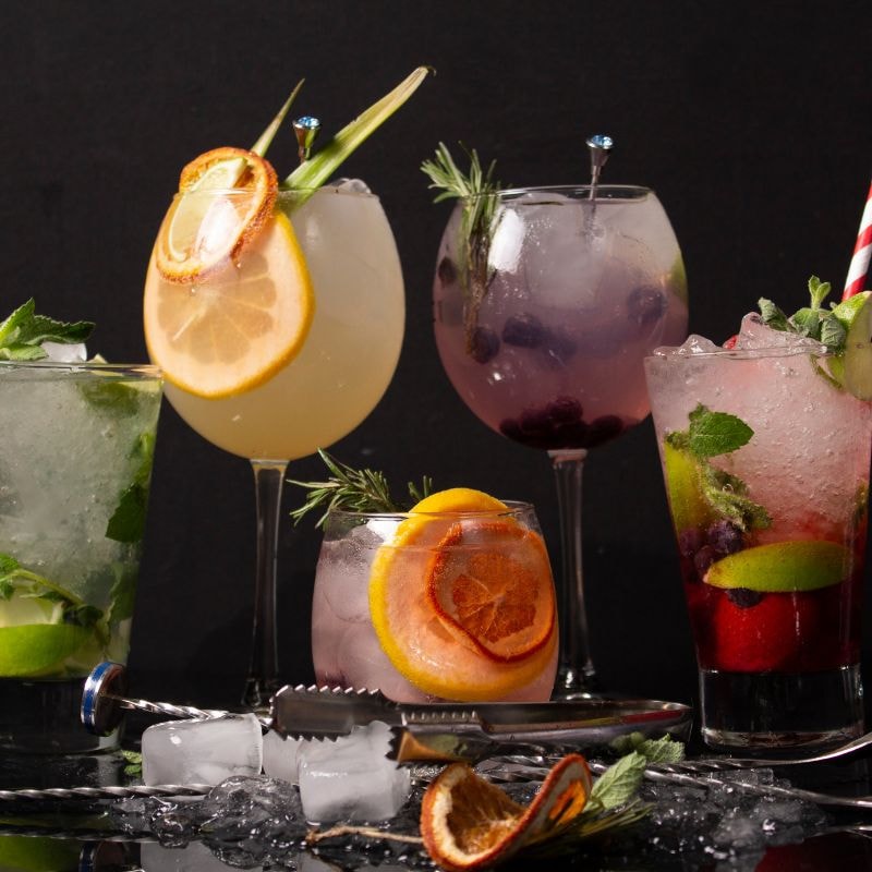 A selection of colorful cocktails, elegantly arranged against a sleek black background to showcase their vibrant hues.