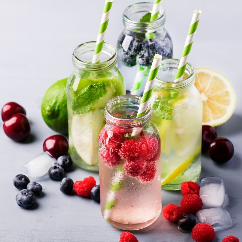 Three glasses filled with water, fresh berries and mint leaves showcase a refreshing non-alcoholic beverage option.